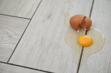 Açık gri ahşap zeminde kırılmış çiğ yumurta ve kabuk. Metin için boşluk