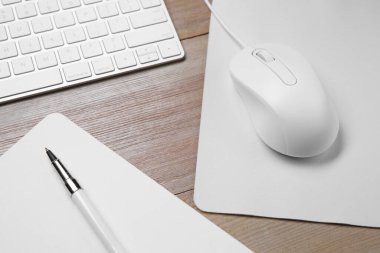Ahşap masa üzerinde fare, defter, kalem ve bilgisayar klavyeli kablo faresi, üst görünüm