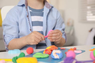 Küçük çocuk masanda hamurla oynuyor, yakın plan.