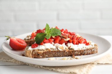 Ricotta peyniri, doğranmış çilek ve beyaz ahşap masada nane şekeri, yakın plan.