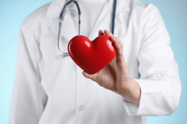 Açık mavi arka planda kırmızı kalpli doktor, seçici odaklanma