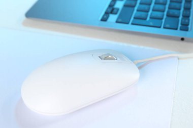 Beyaz masada fare ve dizüstü bilgisayarı olan bilgisayar faresi, yakın plan.