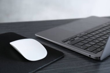 Fare başlı beyaz bilgisayar faresi ve siyah tahta masada dizüstü bilgisayar, yakın plan.