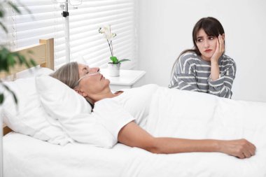 Koma hastası. Hastanede, bilinci kapalı annesinin yanında üzgün genç bir kadın.