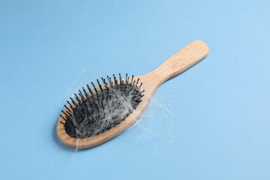 Açık mavi arka planda saçı dökülmüş ahşap fırça