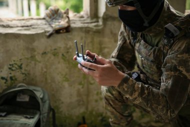 Military mission. Soldier in uniform with drone controller inside abandoned building