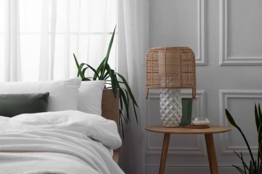 Şık bir oturma odası. Yatak, komodin, lamba ve çiçeklerle dolu.