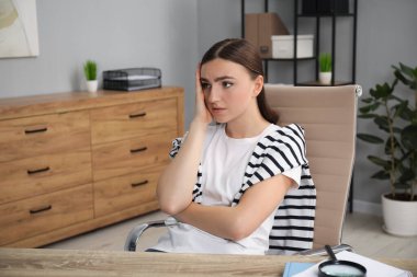 Ofisteki tahta masada utangaç bir kadın.