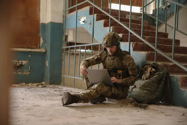 stock image Military mission. Soldier in uniform using laptop inside abandoned building