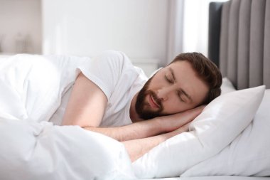 Yakışıklı genç adam, sabahları yatakta uyuyor.