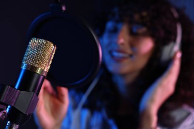 Profesyonel kayıt stüdyosunda mikrofona şarkı söyleyen kadın, seçici odaklanma