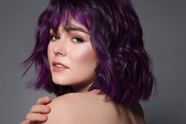 Beautiful young woman with purple hair on grey background