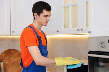 Mutfakta mikrodalga fırın temizleme üniforması giyen profesyonel bir hademe.