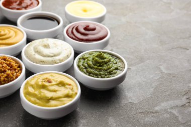 Gri masadaki kaselerde farklı soslar var. Yakın plan. Metin için boşluk