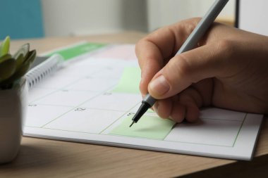 Zaman çizelgesi. Ahşap masada takvim ve yapışkan notlar kullanarak takvim hazırlayan adam, yakın plan