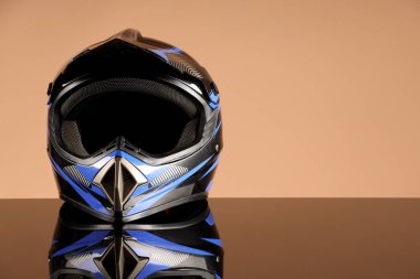 Ayna yüzeyinde bej arka planda güneşliği olan modern motosiklet kaskı. Metin için boşluk