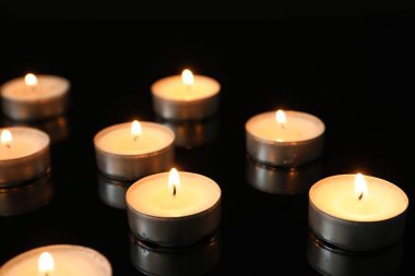 Birçok yanan mum siyah arkaplana karşı ayna yüzeyinde
