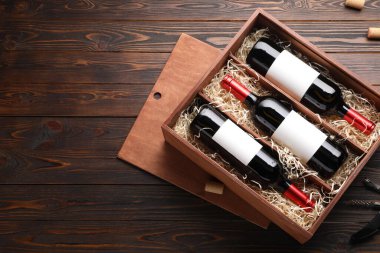 Şarap şişeleri, tirbuşon ve ahşap masa üzerindeki mantarlarla dolu bir kutu. Metin için boşluk