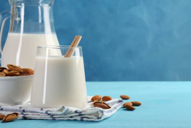 Bir bardak badem sütü, sürahi ve badem açık mavi ahşap masa, metin için yer