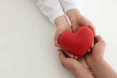 Doktor ve hasta kırmızı kalbi beyaz arka planda tutuyorlar. Metin için boşluk