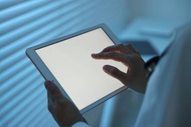 Geceleri hastanede tablet kullanan doktor, yakın plan.