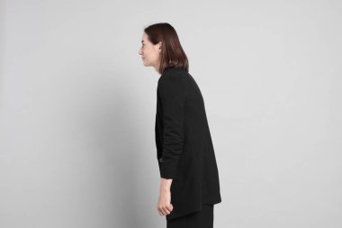 Gri arka planda zayıf duruşu olan kadın.