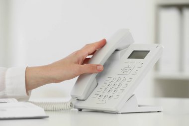 Assistant taking telephone handset at white table, closeup