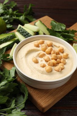 Lezzetli humus, kasede nohut ve ahşap masada taze ürünler.