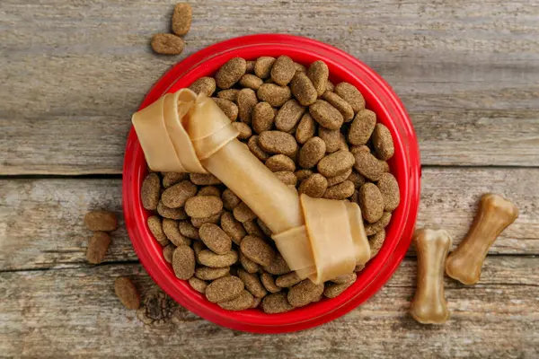 stock image Dry dog food and treats (chew bones) on wooden floor, flat lay