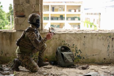 Military mission. Soldier in uniform with drone controller inside abandoned building, space for text