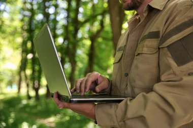 Ormandaki tesisleri inceleyen dizüstü bilgisayarlı Forester, yakın plan.