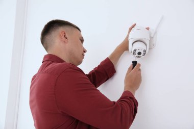 Tornavidalı teknisyen kapalı alandaki duvarlara kamera yerleştiriyor.