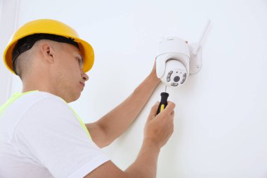 Tornavidalı teknisyen kapalı alanda güvenlik kamerası kuruyor. Düşük açılı.