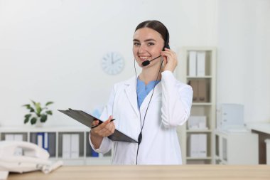 Hastanedeki ahşap masada çalışan profesyonel resepsiyonist.