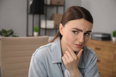 Embarrassed woman in denim jacket in office clipart