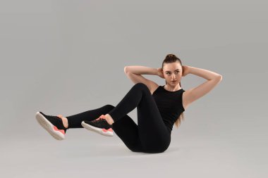 Genç bir kadın hafif arka plan üzerinde aerobik egzersiz yapıyor.