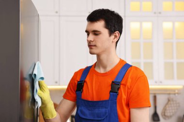 Mutfakta üniformalı temizlik dolabı giyen profesyonel bir hademe.