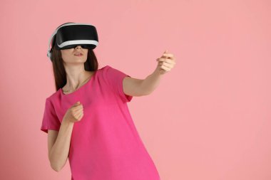 Pembe arka planda sanal gerçeklik kulaklığı kullanan kadın, metin için boşluk