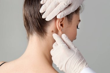 Klinikte kadının benini inceleyen doktor, yakın plan.