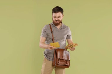 Kahverengi çantalı postacı açık yeşil arka planda mektuplar getiriyor.