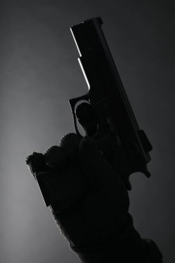 Siyah arka planda silahı olan tehlikeli bir suçlu, yakın plan. Silahlı soygun.