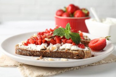 Ricotta peyniri, doğranmış çilek ve beyaz ahşap masada nane şekeri, yakın plan.