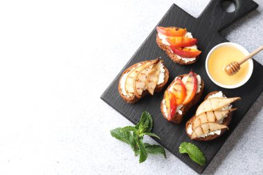 Açık gri masa üzerinde ricotta peynirli ve ballı nefis bruschettalar. Metin için boşluk