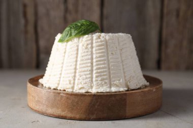 Taze ricotta (krem peynir) ve açık gri masada fesleğen, yakın plan.