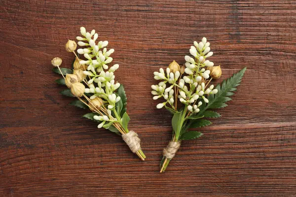 stock image Small stylish boutonnieres on wooden table, top view