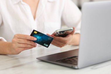 Çevrimiçi bankacılık. Kredi kartı ve dizüstü bilgisayarı olan bir kadın beyaz mermer masadan alışveriş yapıyor, yakın plan.