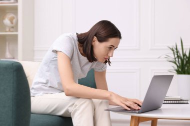 Woman with poor posture using laptop at home clipart