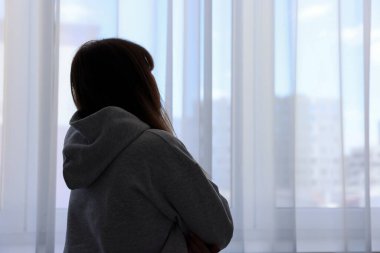 Yalnızlık kavramı. Evinin penceresinin yanında üzgün bir kadın var. Metin için boşluk