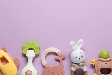 Leylak arka planda farklı bebek tıngırtıları, düz yatış. Metin için boşluk