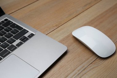 Kablosuz fare ve laptop ahşap masada, yakın plan.